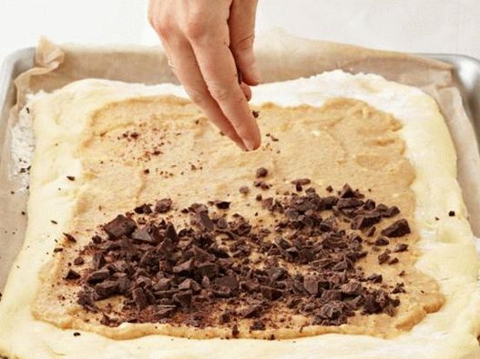 Разстелете тестото с бадемов пълнеж и поръсете с шоколад